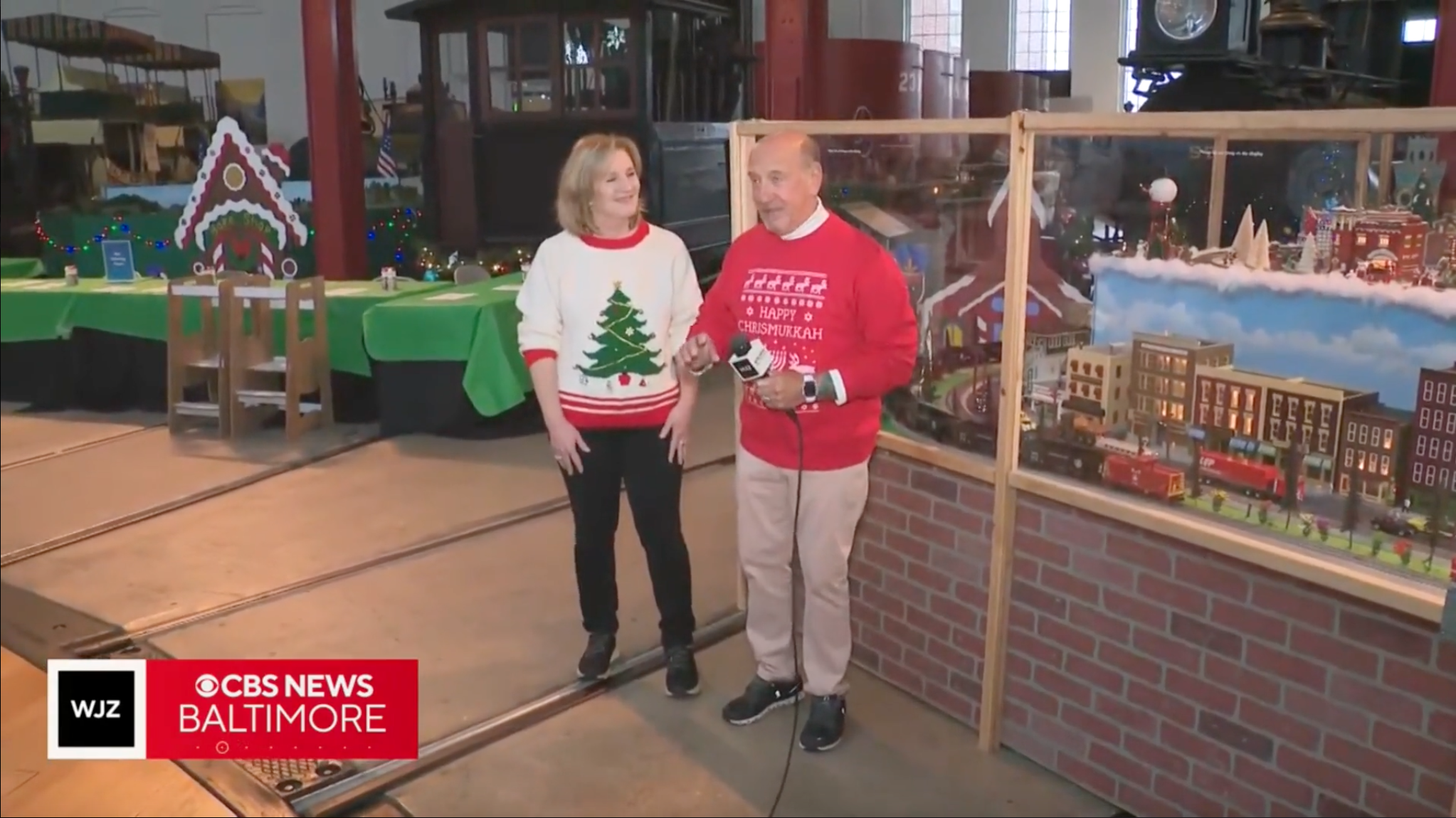 This is an image of a woman and man standing next to a holiday model train display.